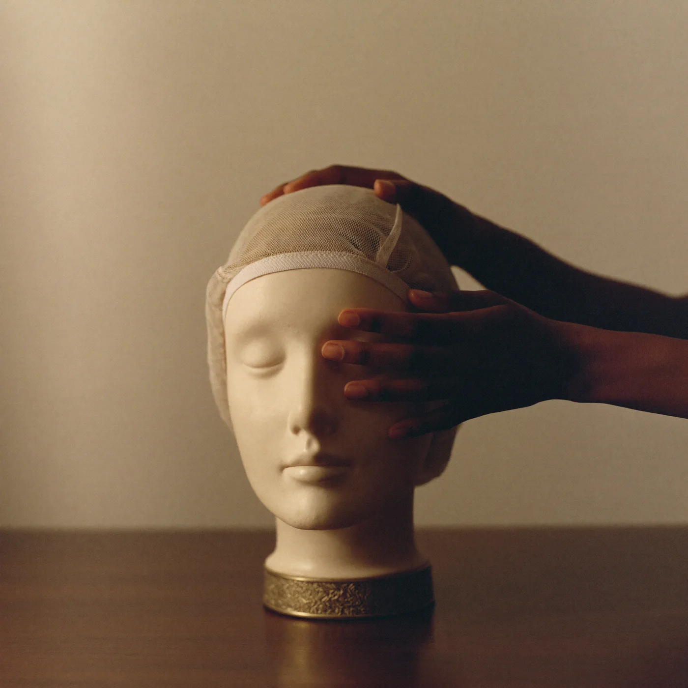 Hands fitting a soft wig cap on a display head
